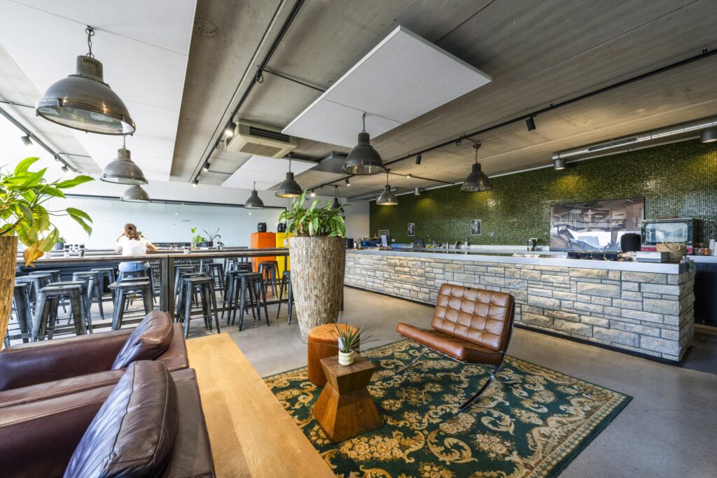 Modern lounge area with leather seating, high tables, and a stone bar at Johan van Hasseltweg.